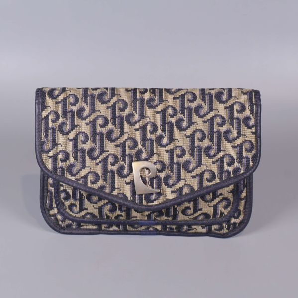 Framsida av clutch med grafiskt monogram och metallspänne