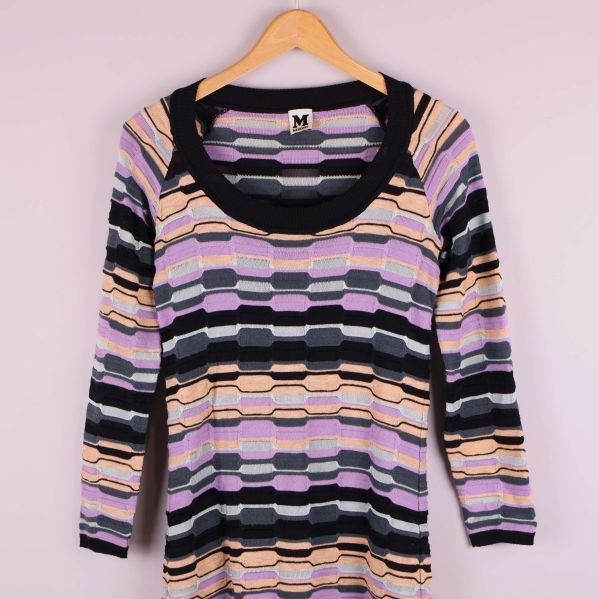 Närbild på halsringning och axel på mönstrad stickad klänning