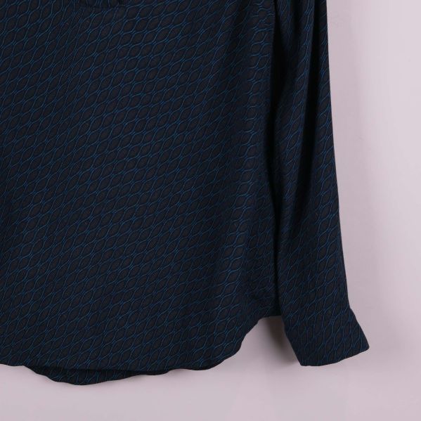 Ärm- och nederkantsdetalj av blåmönstrad topp