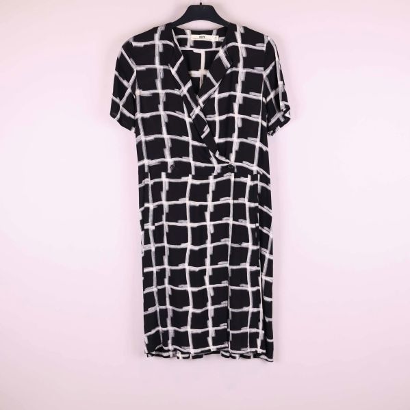 Kortärmad omlottklänning med svartvitt rutmönster hänger på galge