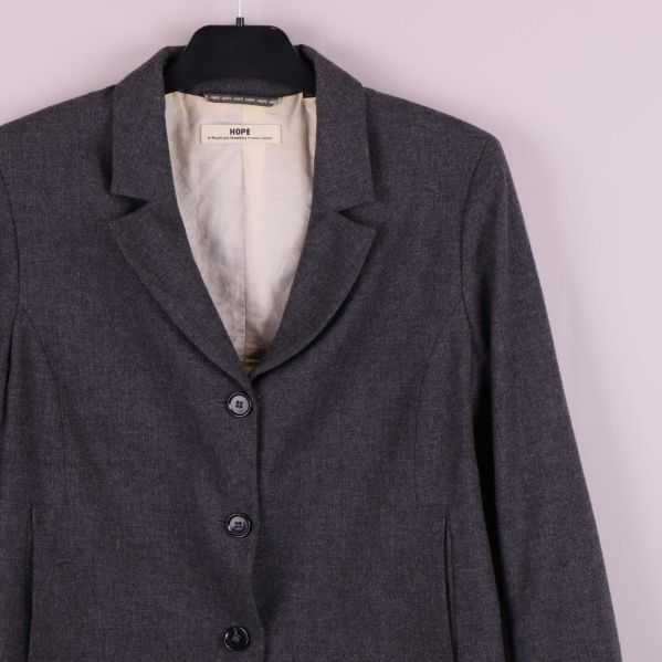 Övre del av grå kavaj och krage med knappdetaljer