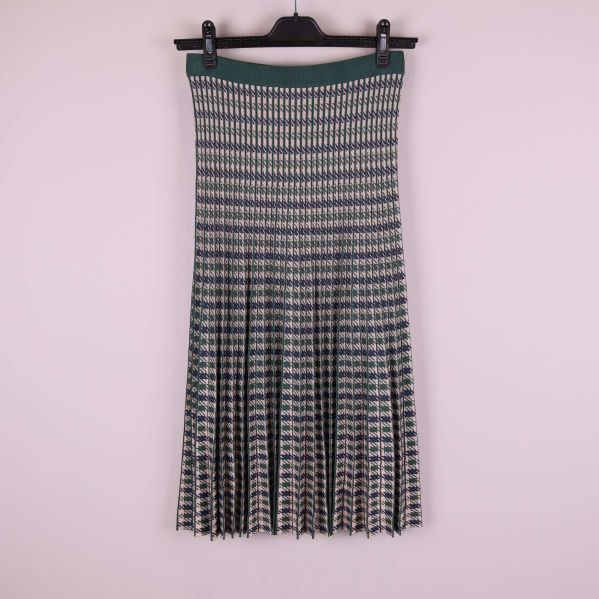 Plisserad kjol med grönt och blått mönster visas på galge