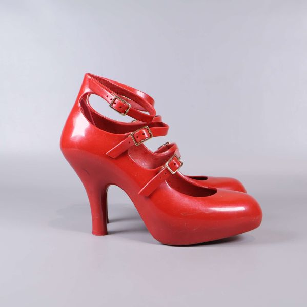 Röd pumps från sidan med markerad klack och remmar