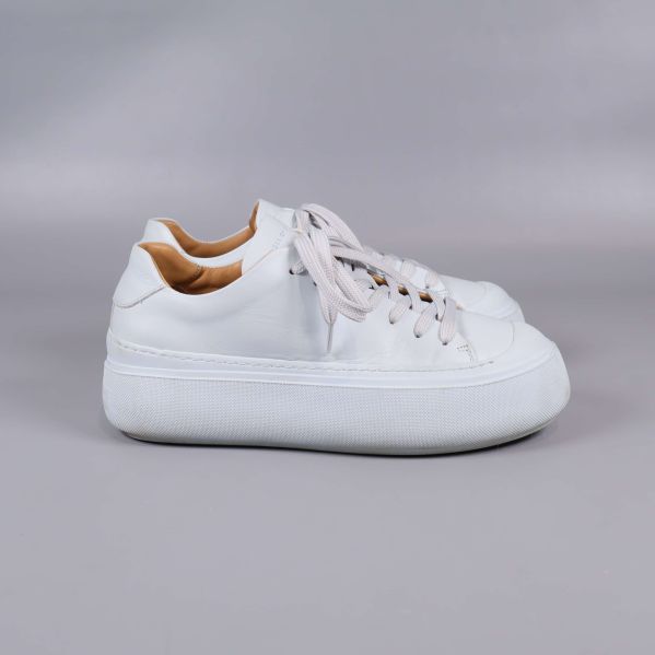 Vita sneakers i profil på grå bakgrund