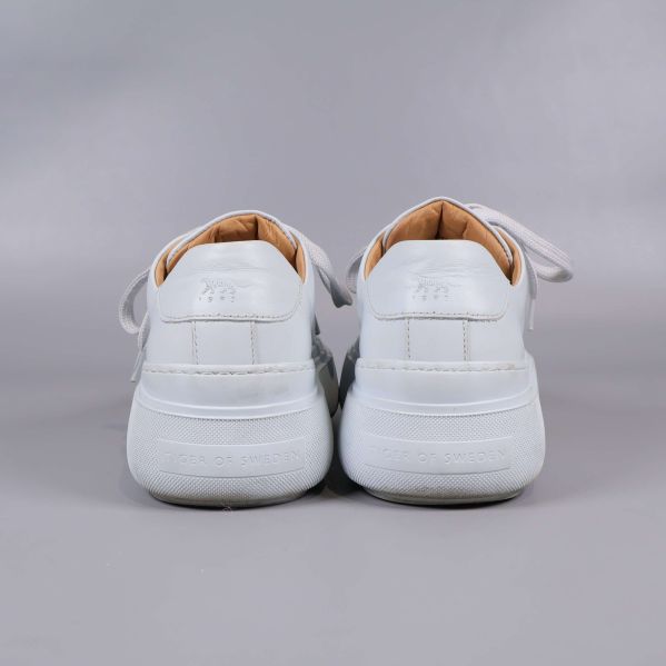 Baksidan av vita sneakers visar präglad logga