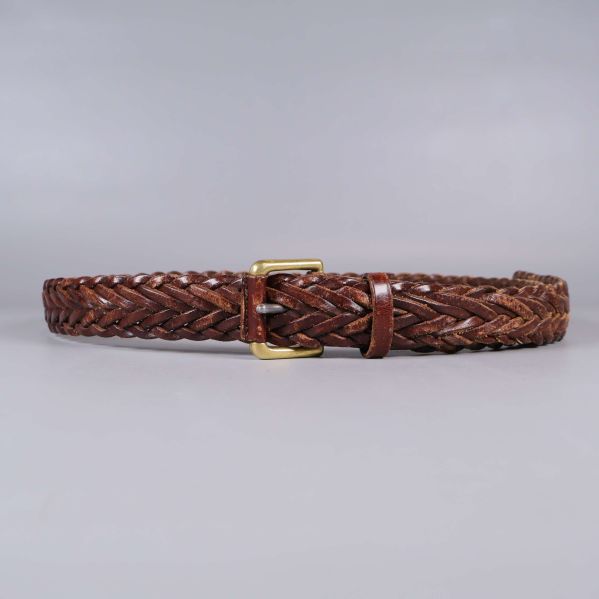 Helt flätat brunt läderbälte med mässingsspänne mot grå bakgrund