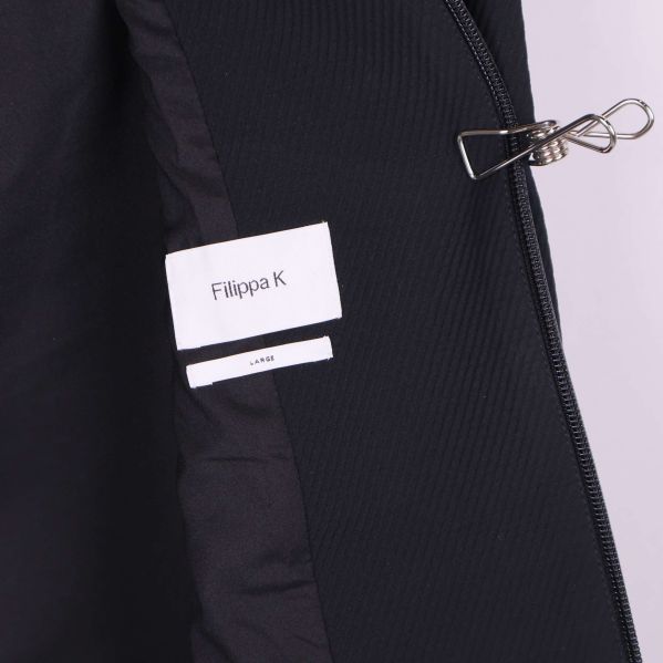 Etikett med Filippa K och storlek large i svart jacka