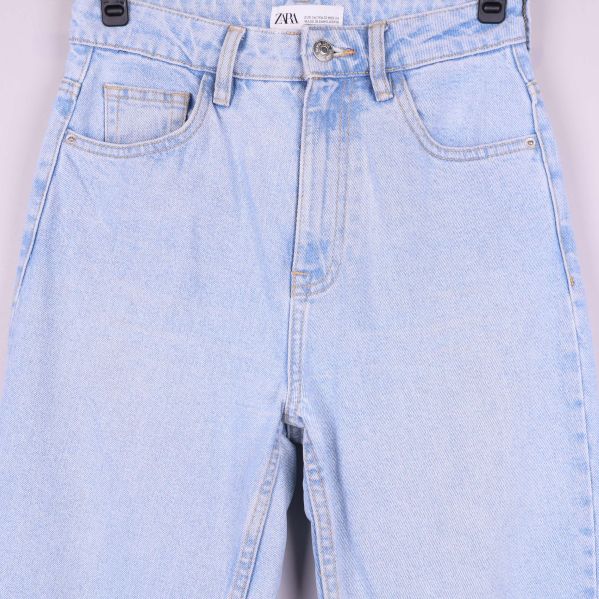 Närbild på jeansens midjedetaljer och fickor