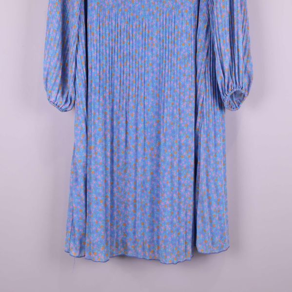 Klänningens nedre del visar plisserat tyg och blommigt mönster