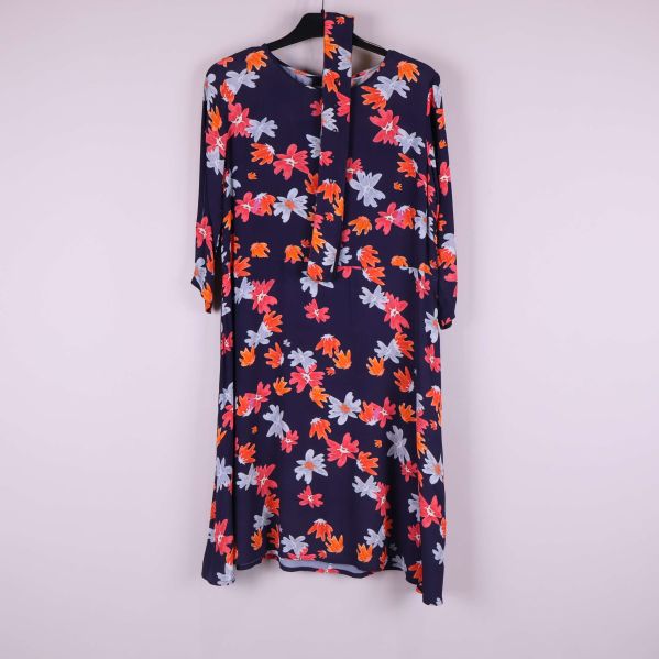 Blommig klänning i marinblått med knytband upphängd på galge