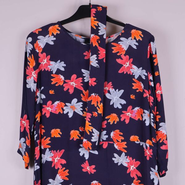 Övre del av klänning visar knytband och blommönster