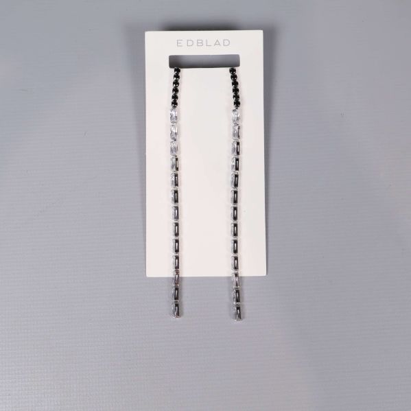Långa örhängen med svarta och klara stenar på vit display