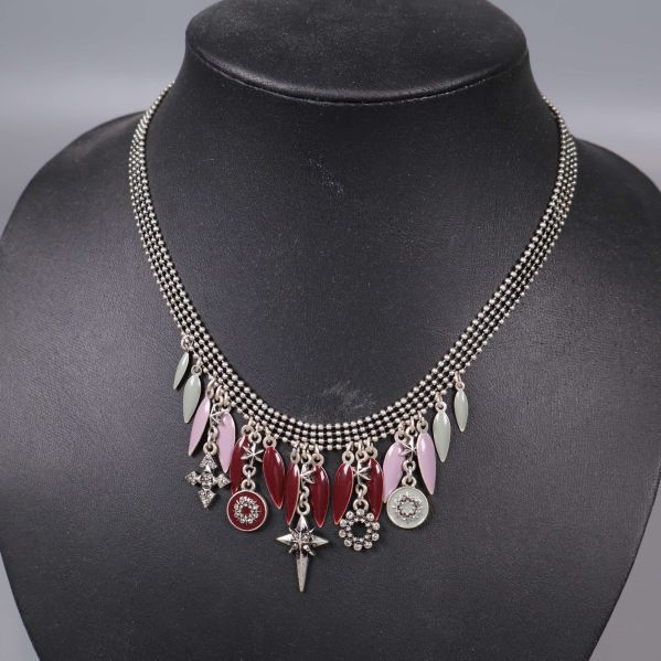 Närbild på halsbandets dekorativa röda och silverdetaljer