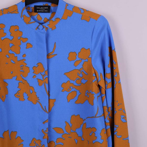 Närbild på blommigt tyg och skjortans framstycke