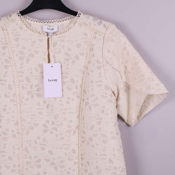 Närbild på hals och axel med spetskant och etikett