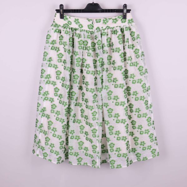 Vit kjol med gröna blommor bakifrån på galge