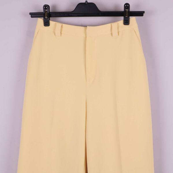 Framstycke av byxan med stängd dragkedja och vida ben