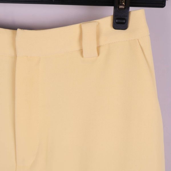 Detaljbild på midja och bälteshällor i ljusgult tyg