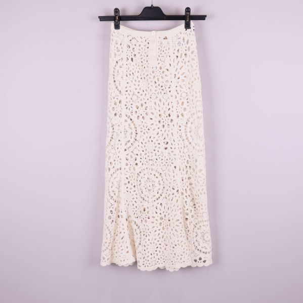 Framsida av lång krämvit virkad kjol på galge