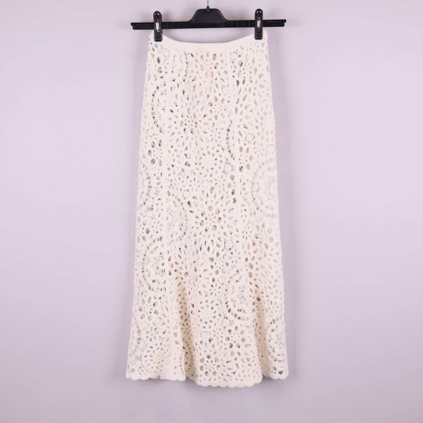 Baksida av lång krämvit virkad kjol på galge