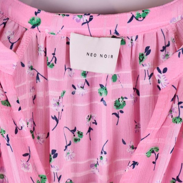 Närbild på Neo Noir-märke och blommigt tyg