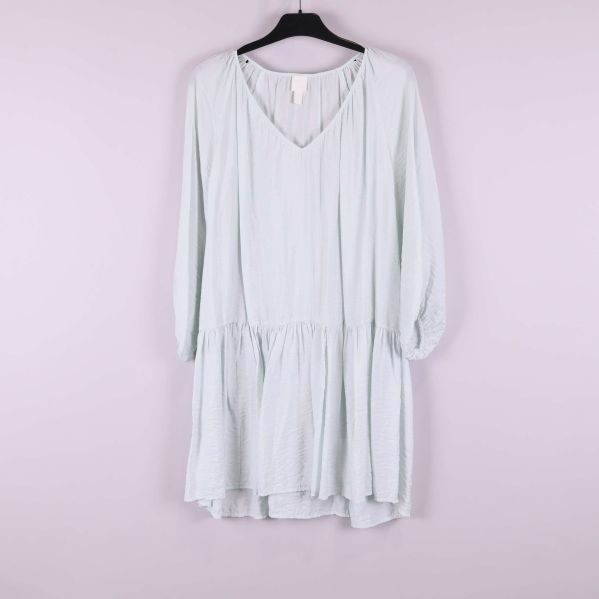 Ljus klänning med v-ringning och volangkant framifrån