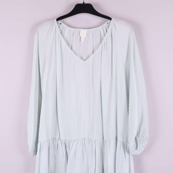 V-ringning och axelparti på ljus klänning tydligt