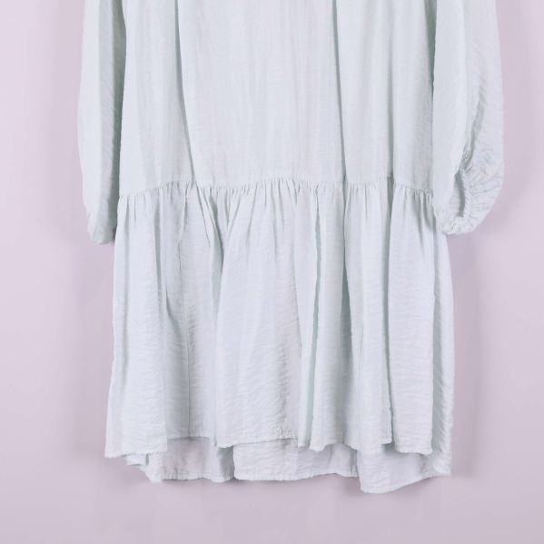 Volangkantad nederdel på ljus klänning i närbild