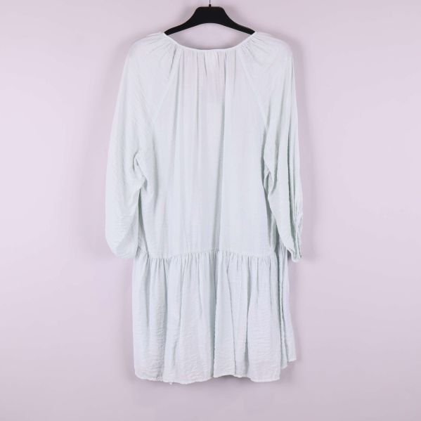 Ljus klänning med vidd och volangkant bakifrån