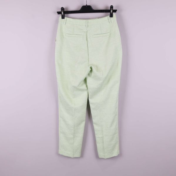 Ljusgröna byxor upphängda mot ljus bakgrund, helbild bakifrån