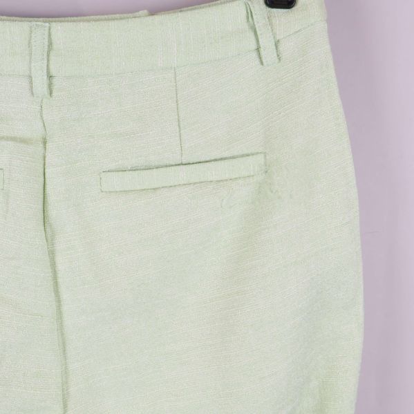 Närbild på ficka och tygstruktur på ljusgröna byxor