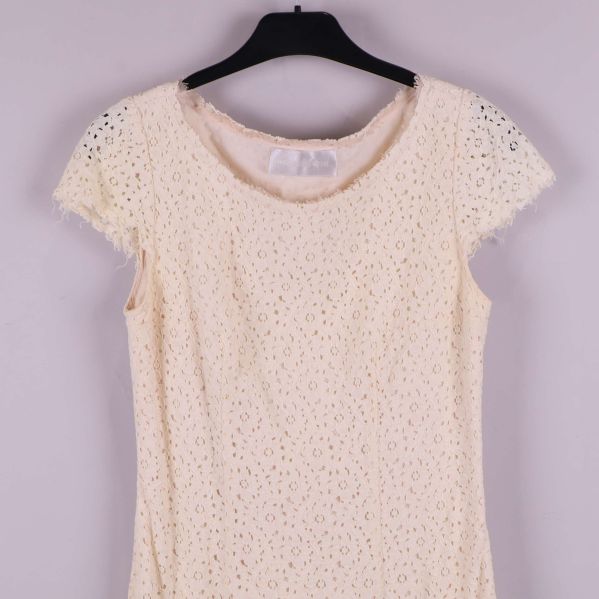 Närbild på klänningens överdel och ärm med spetsmönster