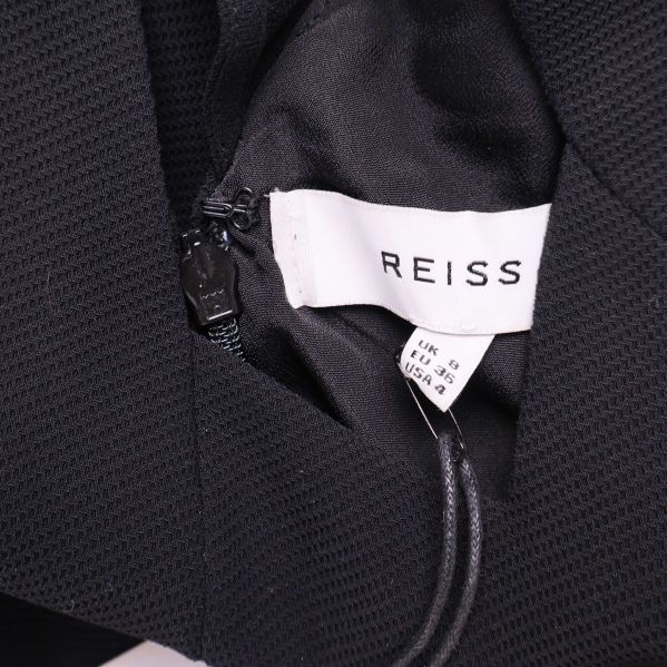 Vit etikett med Reiss-logotyp hängande från klänningen