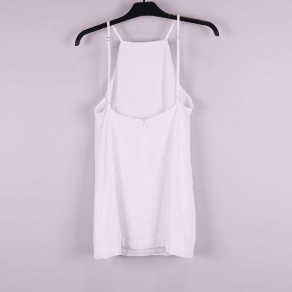 Vit topp med tunna axelband bakifrån på galge