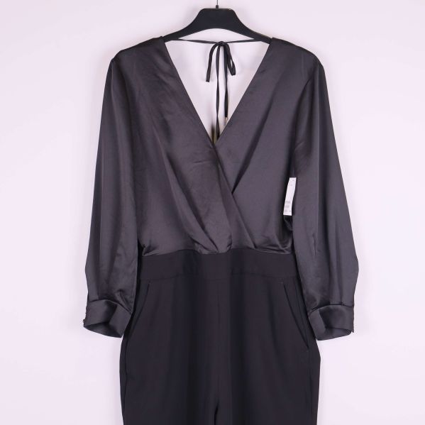 Närbild framtill på svart jumpsuit med insnitt och fickor