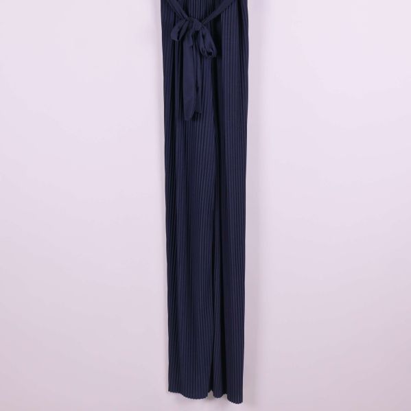 Plisserade långa ben på mörkblå jumpsuit i närbild