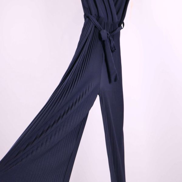 Närbild på vida plisserade ben och midjeband på jumpsuit