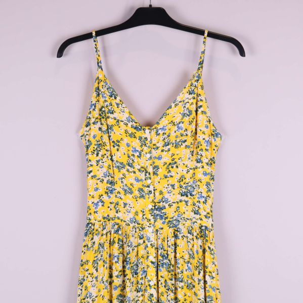Överdel av gulblommig klänning, v-ringning och smala axelband i närbild