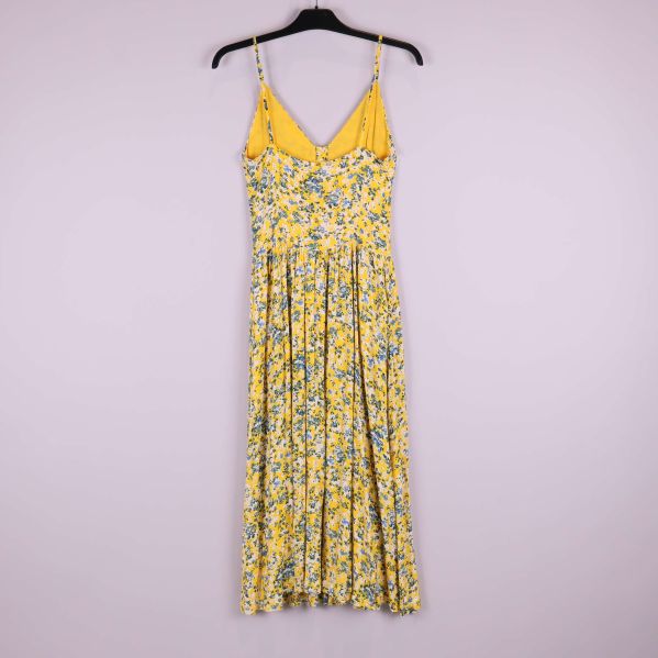 Baksida av gulblommig klänning med v-ringning och tunt axelband