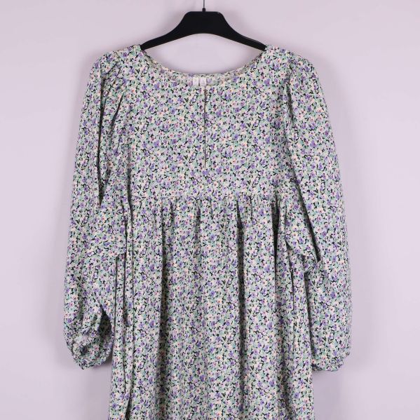 Övre del av klänningen med blommigt mönster och rund hals