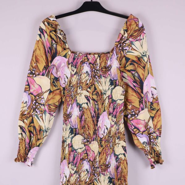 Närbild av klänningens överdel med smock och blommigt tyg