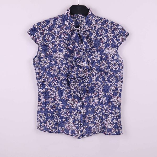 Blommig kortärmad blus med volang framtill upphängd på galge