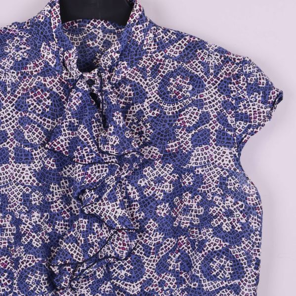 Närbild på volangdetalj och blommig färgkombination på blus