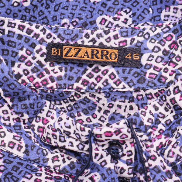 Närbild på Bizzarro-logotyp och storlekslapp på färgad blus