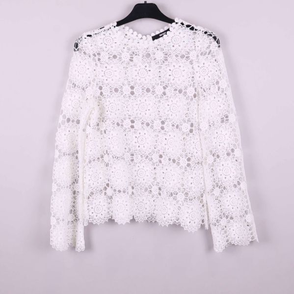 Baksidan av vit spetsblus med knappdetalj vid nacken
