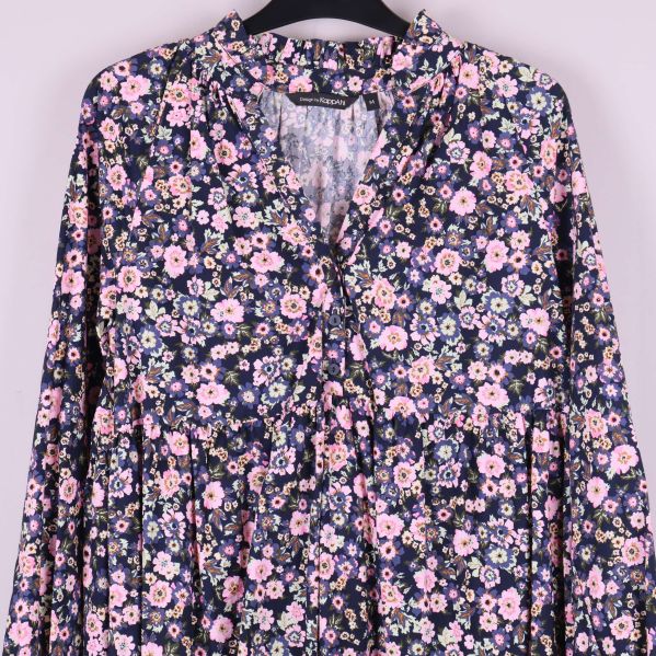 Detaljbild på övre delen av klänningens blommönster och öppning