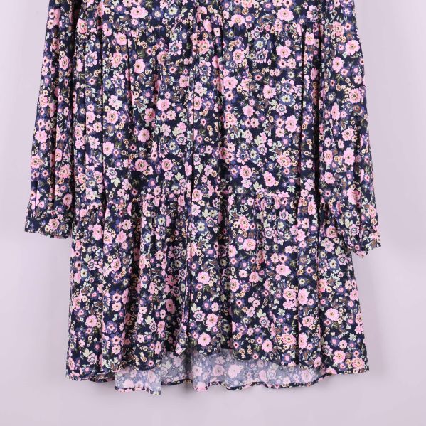 Närbild på blommiga volanger i nedre delen av klänningen