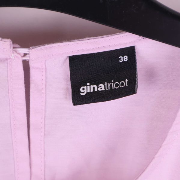 Närbild på märkeslapp ginatricot och storlek 38 i klänning