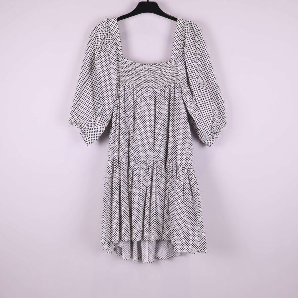 Prickig klänning med puffärm hängande mot ljus bakgrund