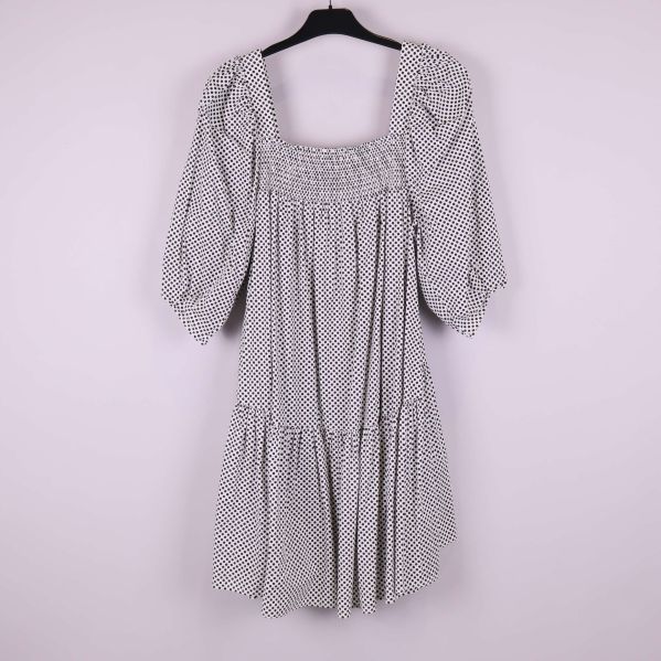 Baksidan av prickig klänning med smockdetalj upptill